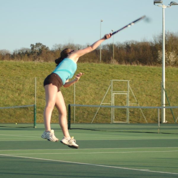 Lady returning a shot on the tennis court at Surrey Sports Park