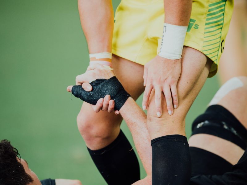 rugby player helping another player get up after injuring their knee